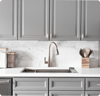 Une cuisine avec des armoires grises et un plan de travail en marbre.